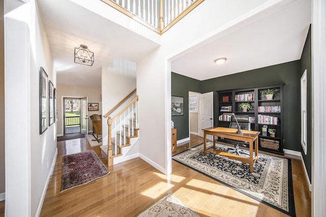 office area with baseboards, a high ceiling, and wood finished floors