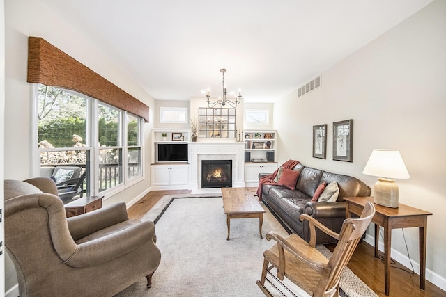 living area featuring visible vents, baseboards, an inviting chandelier, and wood finished floors