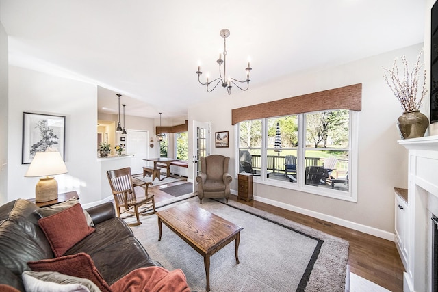 living room featuring baseboards, an inviting chandelier, wood finished floors, and a fireplace with flush hearth