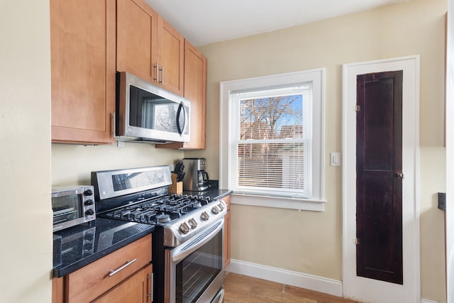 16890 Monica St, Detroit, MI 48221 - kitchen featuring light wood-style flooring, dark stone countertops, appliances with stainless steel finishes, and baseboards