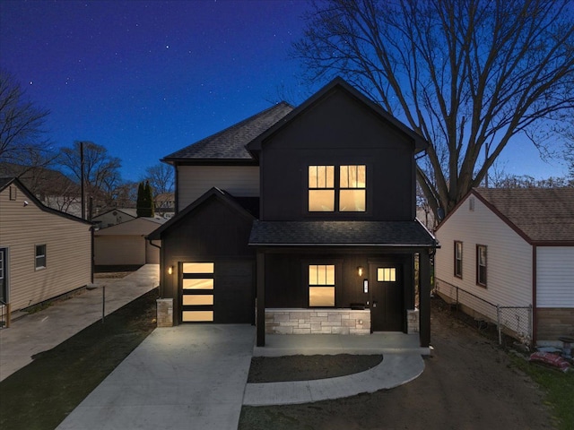 contemporary house featuring concrete driveway, roof with shingles, stone siding, board and batten siding, and a porch