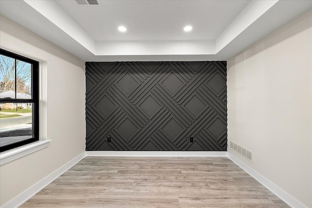 spare room featuring a tray ceiling, baseboards, and visible vents
