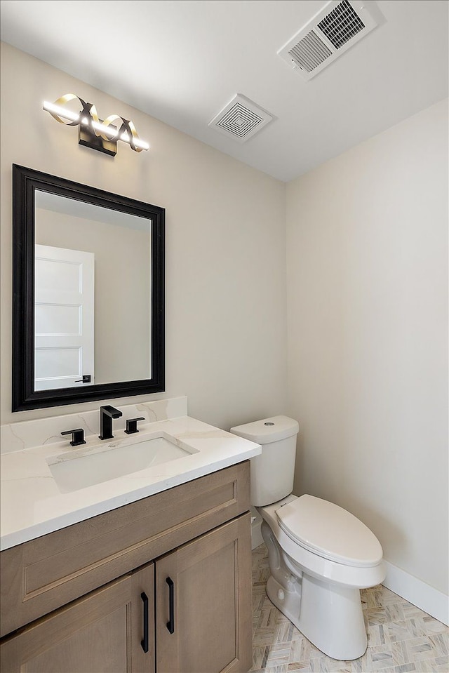 half bath featuring visible vents, toilet, vanity, and baseboards