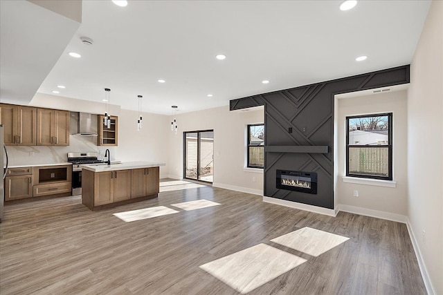 kitchen with open floor plan, light countertops, appliances with stainless steel finishes, and wall chimney range hood