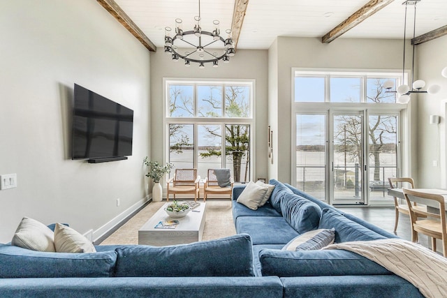 living room with an inviting chandelier, beamed ceiling, a towering ceiling, wooden ceiling, and baseboards