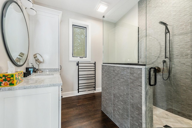 full bath with baseboards, a stall shower, wood finished floors, and vanity