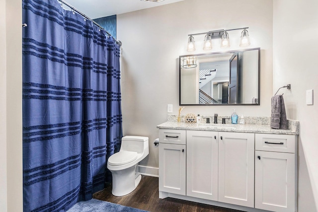 bathroom featuring baseboards, a shower with shower curtain, toilet, vanity, and wood finished floors