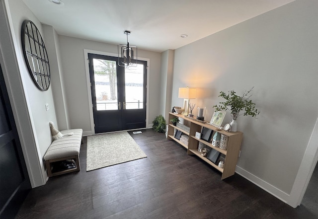 foyer entrance with dark wood-type flooring, french doors, baseboards, and a notable chandelier