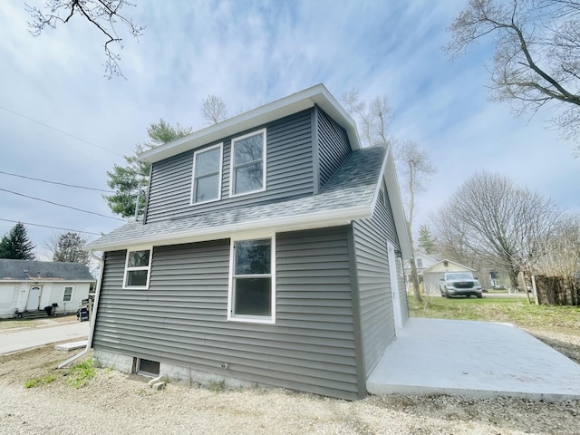 view of side of home with roof with shingles