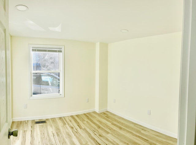unfurnished room featuring visible vents, baseboards, and wood finished floors