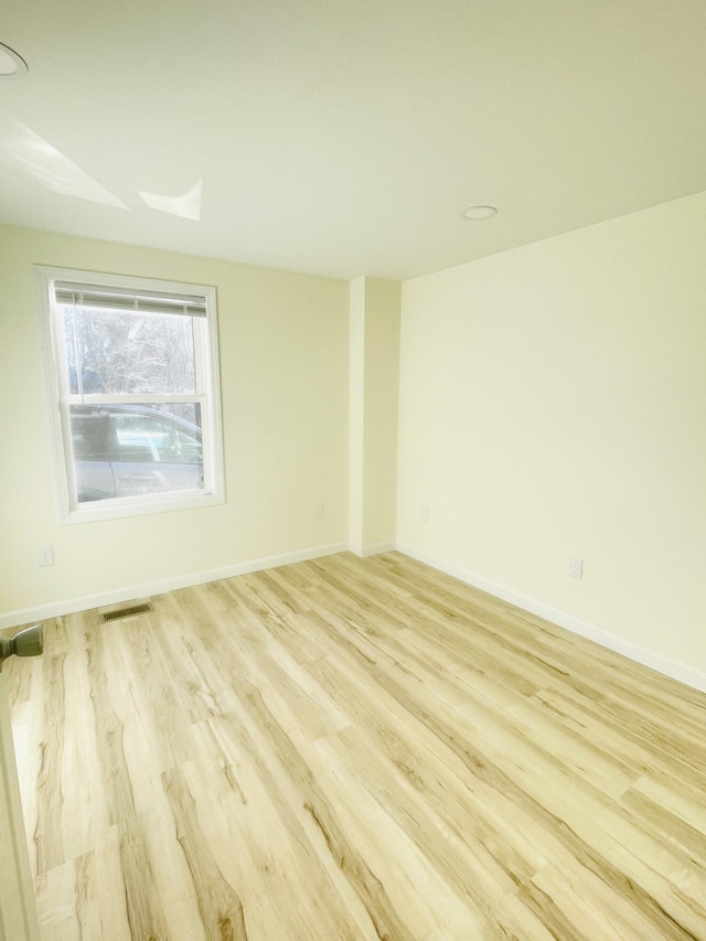 unfurnished room with light wood finished floors, baseboards, and visible vents