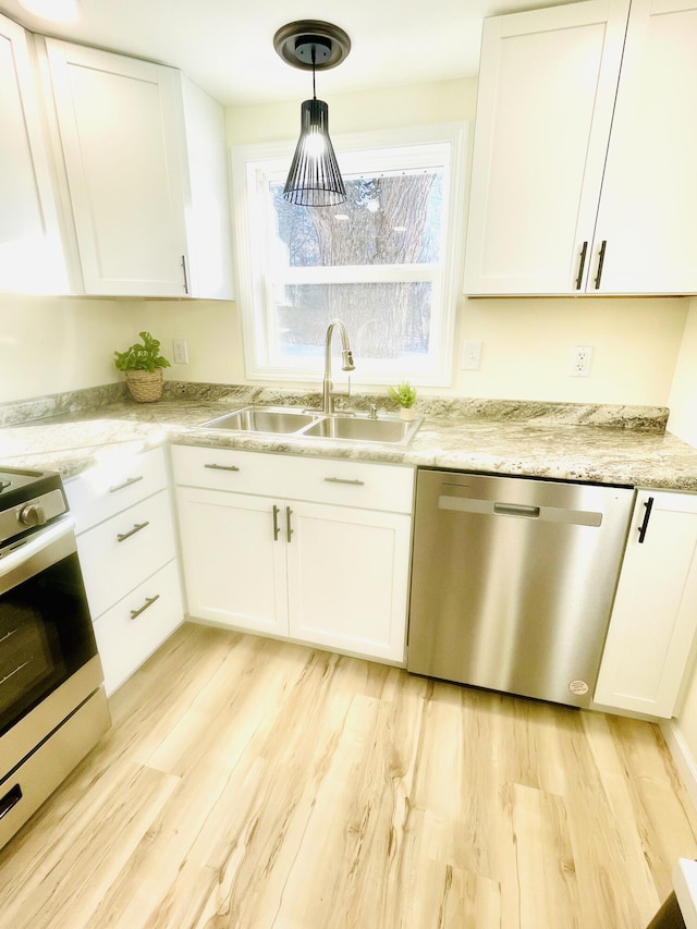 kitchen featuring pendant lighting, light wood-type flooring, white cabinets, a sink, and stainless steel appliances