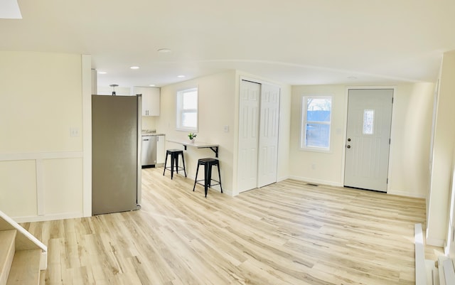 foyer entrance with a decorative wall, light wood finished floors, recessed lighting, and a wealth of natural light