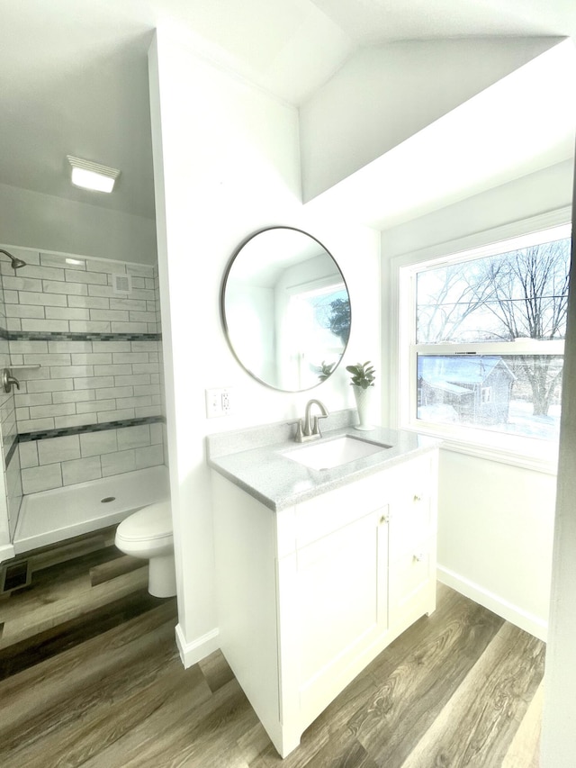 full bathroom with a shower stall, vanity, vaulted ceiling, toilet, and wood finished floors