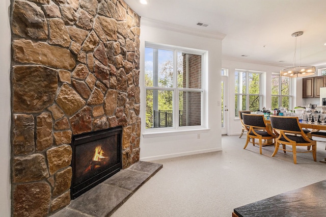 carpeted living room with a stone fireplace, visible vents, crown molding, baseboards, and an inviting chandelier