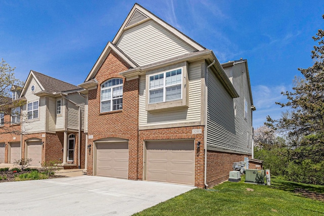 view of front of home with brick siding, an attached garage, driveway, and a front lawn