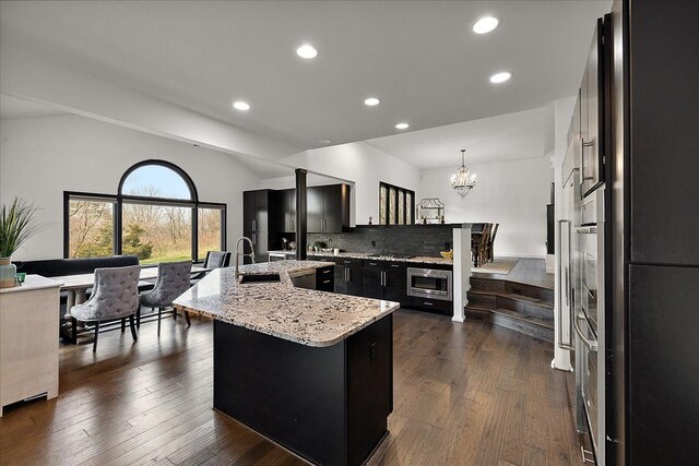 1194 Eagle Nest, Milford, MI 48381 - kitchen with dark cabinets, an island with sink, a chandelier, appliances with stainless steel finishes, and dark wood finished floors