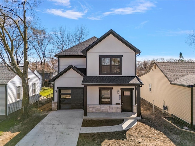 view of front of house with roof with shingles, driveway, stone siding, a garage, and covered porch