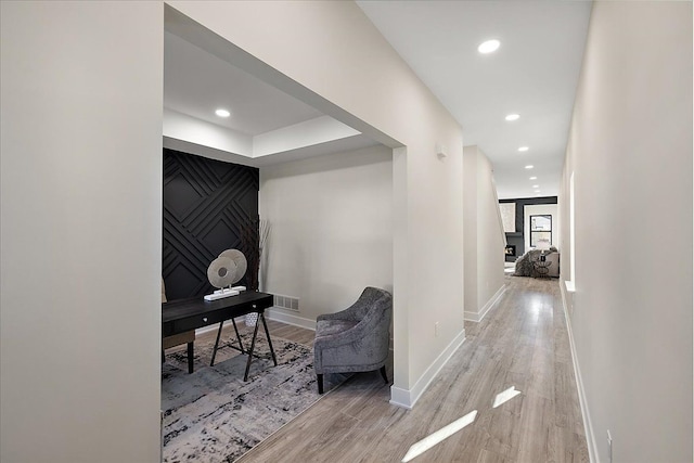 hallway with wood finished floors, baseboards, visible vents, and recessed lighting
