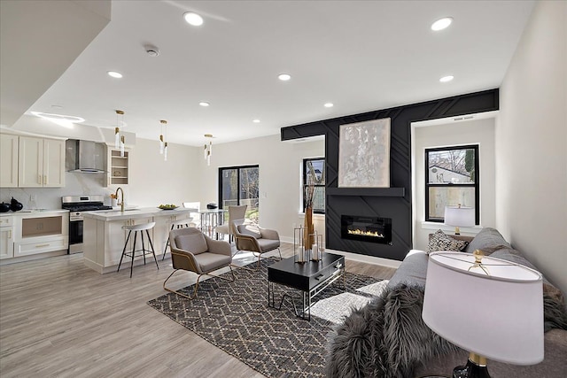living room featuring light wood finished floors, a fireplace, and recessed lighting