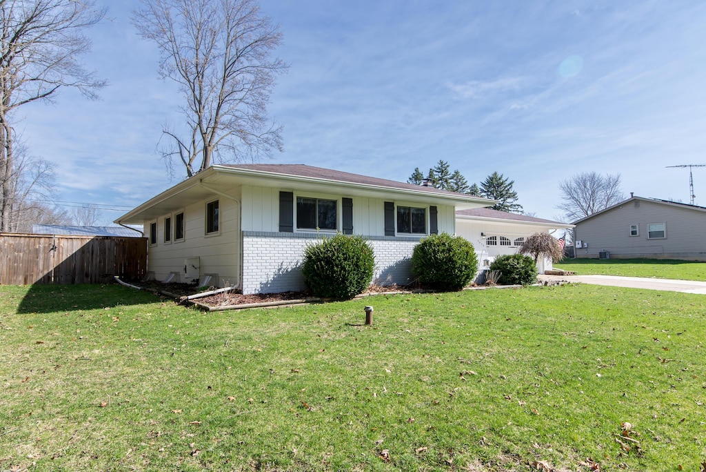 ranch-style home featuring driveway, a front yard, fence, and brick siding