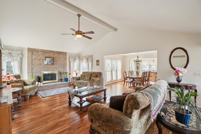 living area with wood-type flooring, ceiling fan with notable chandelier, beamed ceiling, and a healthy amount of sunlight