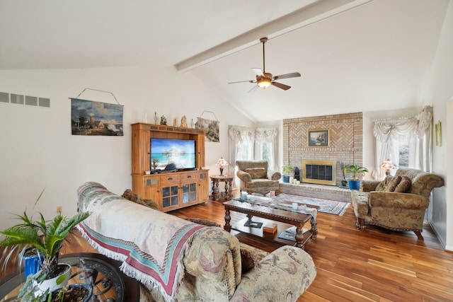 living room with lofted ceiling with beams, a fireplace, a ceiling fan, visible vents, and wood-type flooring
