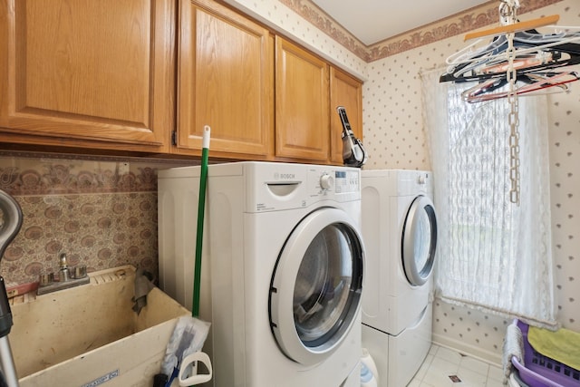 laundry area featuring separate washer and dryer, a sink, wallpapered walls, cabinet space, and tile patterned floors
