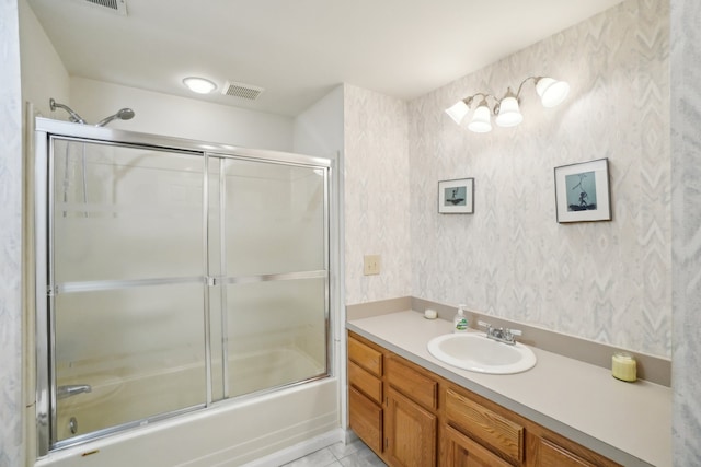 bathroom with wallpapered walls, vanity, combined bath / shower with glass door, and visible vents