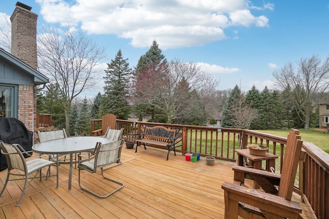 wooden terrace featuring outdoor dining area and a lawn