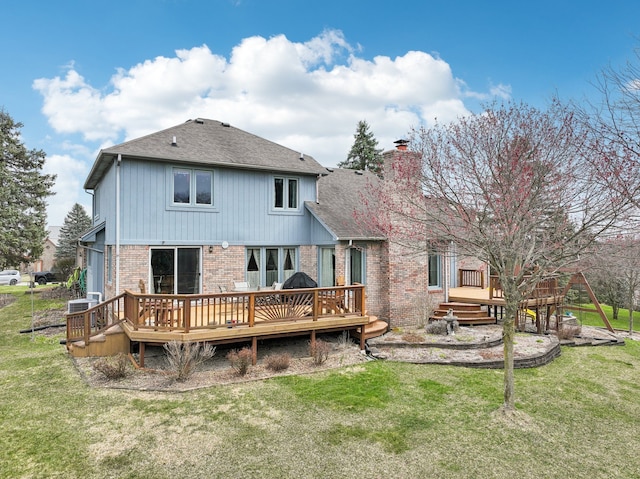 back of property with brick siding, a deck, a chimney, and a lawn