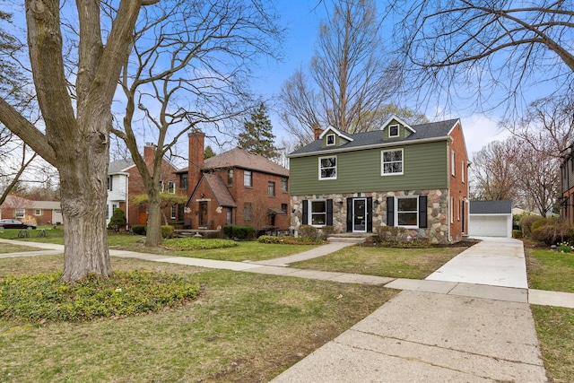 view of front of house featuring a detached garage, a front yard, and stone siding