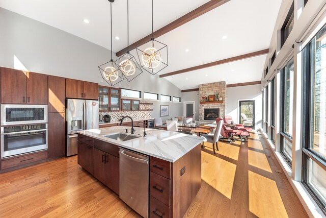 10485 Hadley Rd, Gregory, MI 48137 - kitchen featuring light wood-type flooring, a fireplace, beamed ceiling, stainless steel appliances, and a sink