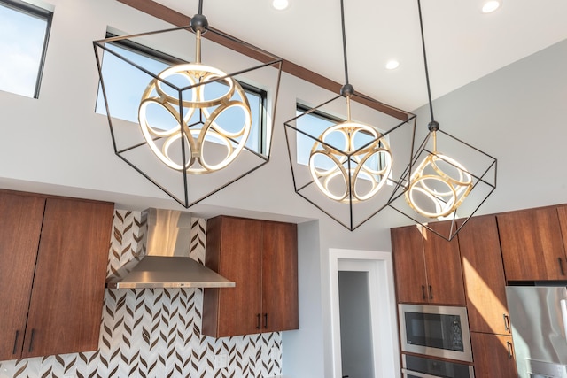 10485 Hadley Rd, Gregory, MI 48137 - room details with wall chimney exhaust hood, stainless steel appliances, decorative light fixtures, brown cabinets, and a notable chandelier
