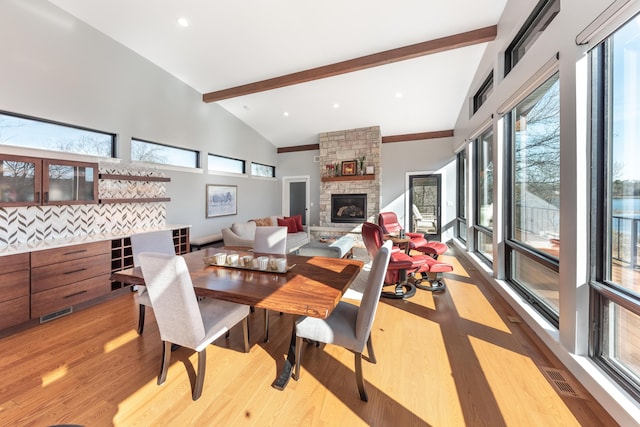 10485 Hadley Rd, Gregory, MI 48137 - dining space featuring a fireplace, light wood-style flooring, visible vents, beamed ceiling, and high vaulted ceiling