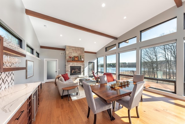 10485 Hadley Rd, Gregory, MI 48137 - dining space with a fireplace, light wood-style floors, visible vents, beam ceiling, and high vaulted ceiling