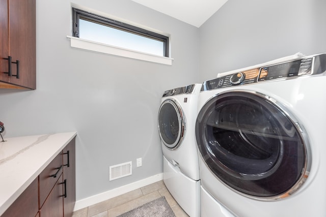 10485 Hadley Rd, Gregory, MI 48137 - clothes washing area featuring visible vents, baseboards, cabinet space, washing machine and dryer, and light tile patterned flooring