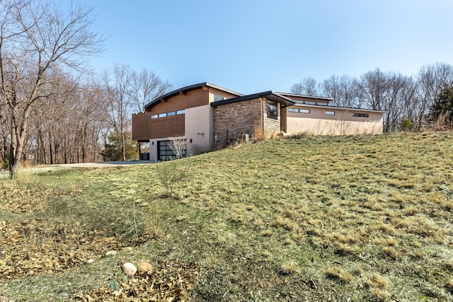10485 Hadley Rd, Gregory, MI 48137 - view of side of property with stone siding, a lawn, a garage, and stucco siding