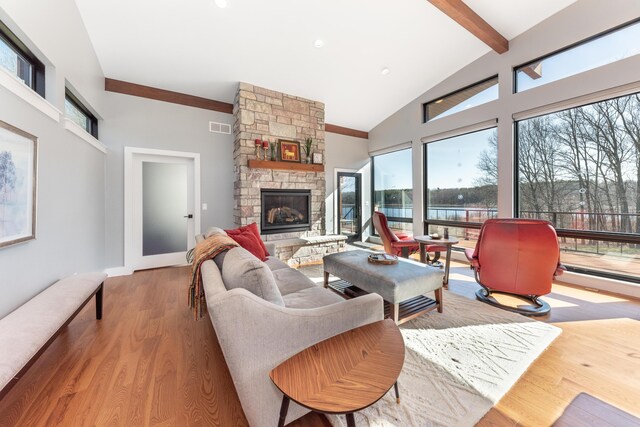 10485 Hadley Rd, Gregory, MI 48137 - living room featuring high vaulted ceiling, visible vents, a stone fireplace, wood finished floors, and beam ceiling