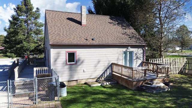 rear view of property with a wooden deck, a yard, roof with shingles, fence, and a gate