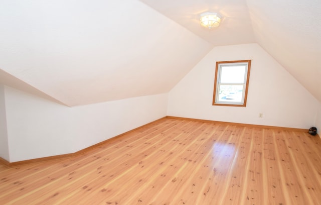 bonus room with light wood-type flooring, baseboards, and lofted ceiling