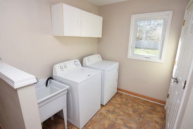 laundry area with stone finish flooring, baseboards, washing machine and clothes dryer, and cabinet space