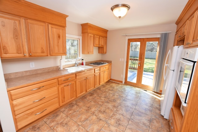 kitchen featuring light countertops, a healthy amount of sunlight, a sink, and white appliances