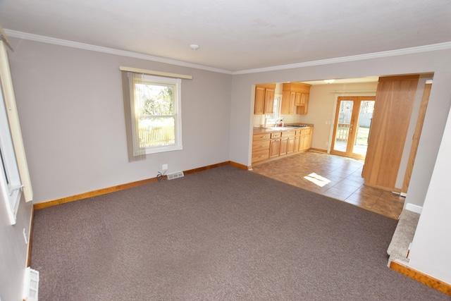 unfurnished living room with carpet flooring, ornamental molding, and a wealth of natural light