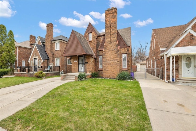 18645 Cherrylawn St, Detroit, MI 48221 - tudor home with brick siding, a front yard, fence, a gate, and a chimney