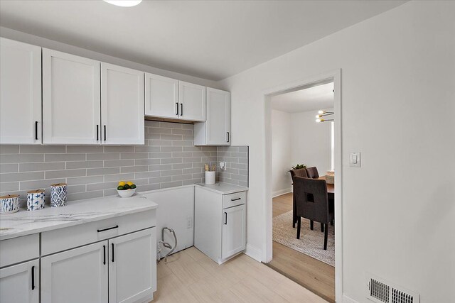 18645 Cherrylawn St, Detroit, MI 48221 - kitchen featuring light stone countertops, visible vents, white cabinetry, and backsplash