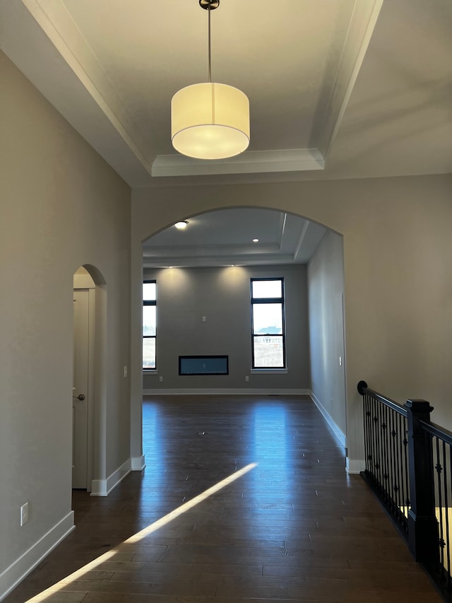 60671 Town Square St, New Hudson, MI 48165 - unfurnished living room featuring a tray ceiling, wood-type flooring, arched walkways, and baseboards