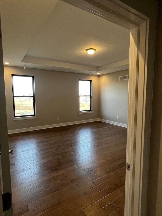 60671 Town Square St, New Hudson, MI 48165 - spare room with dark wood-type flooring, visible vents, baseboards, and a raised ceiling