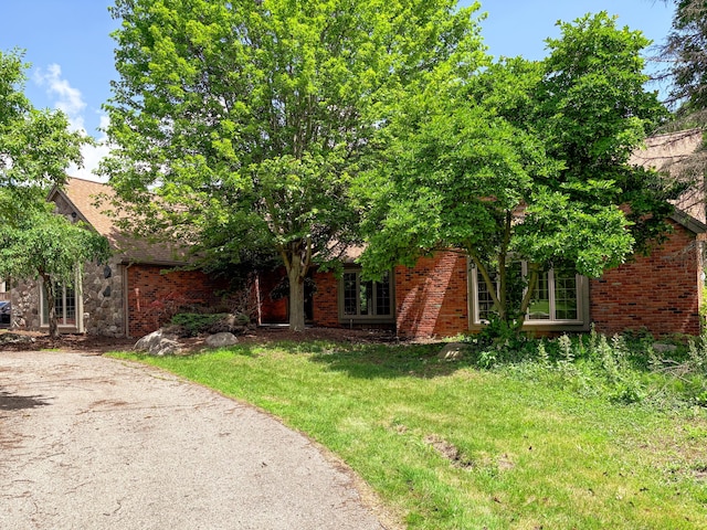 4489 Cranbrook Trl, Orchard Lake, MI 48323 - view of property hidden behind natural elements featuring a front lawn and brick siding