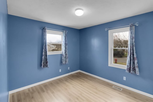 spare room with visible vents, baseboards, and wood finished floors